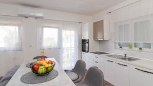 Una cucina moderna con mobili bianchi, forno integrato e lavello in acciaio inossidabile.