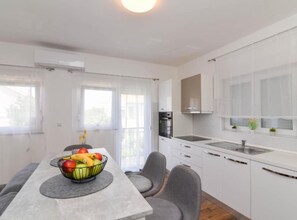 A modern kitchen with white cabinets, a built-in oven, and a stainless steel sink. - One Bedroom Apartment with Terrace and Sea View (Sukosan)