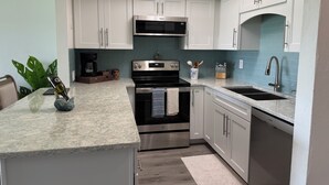 A modern kitchen with white cabinets, stainless steel appliances, a marble countertop, and a skylight. - Waterfront Flagler Beach Retreat I 2 King Beds I 2 Full Baths I Kayaks (Flagler Beach)