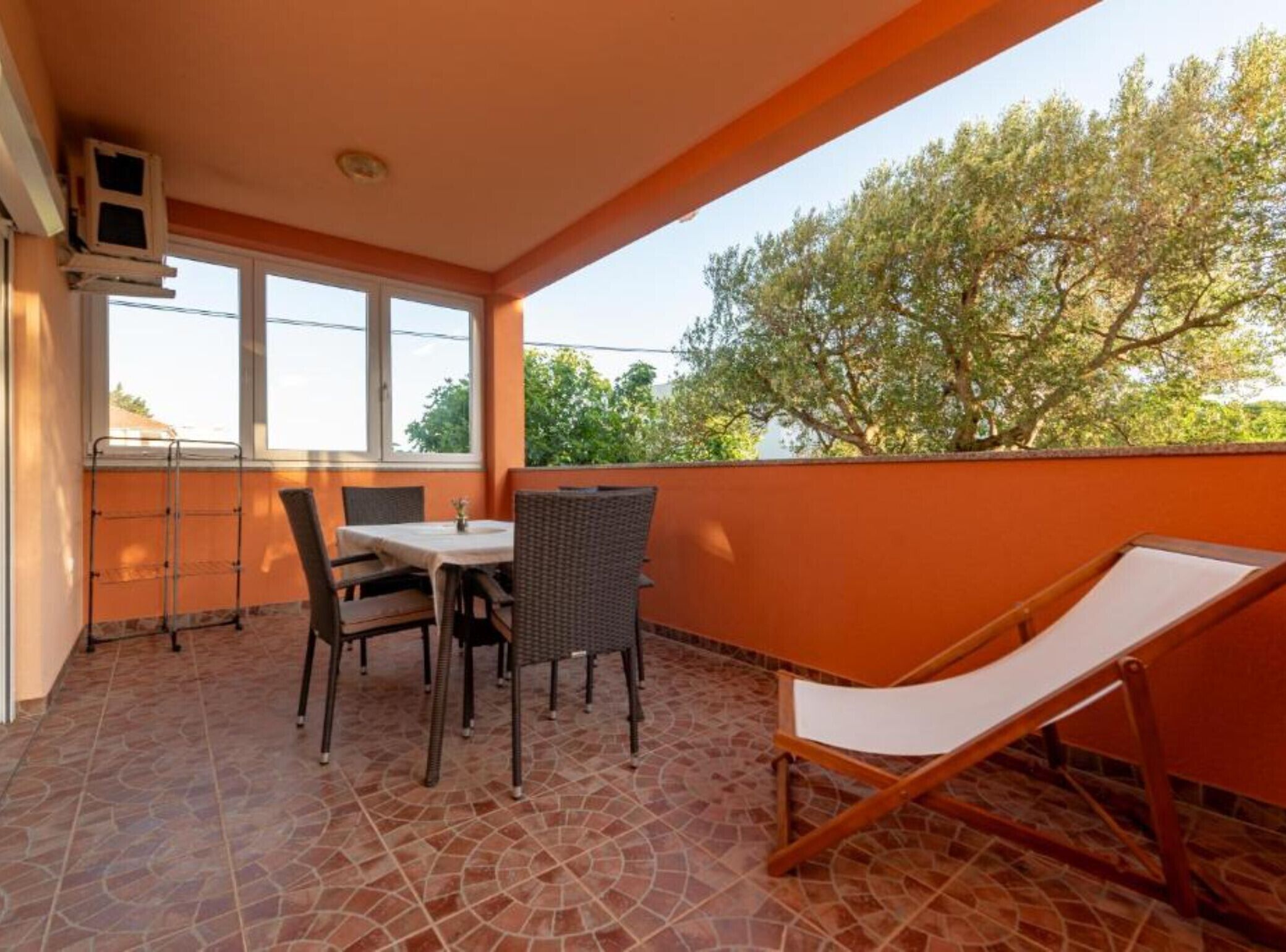 Un balcon avec une table et des chaises, un fauteuil de relaxation et une vue sur les arbres.