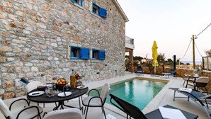A stone building with a pool, outdoor seating, and a yellow umbrella. - Villa with pool and sea view (Pasman)