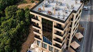 Un hôtel à plusieurs étages doté d’une terrasse sur le toit, d’une piscine extérieure et de nombreux balcons.