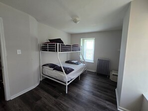Une chambre avec un lit superposé, un radiateur et une fenêtre.