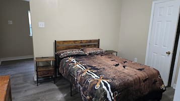 Un dormitorio con una cama de madera, una mesita de noche y una puerta.