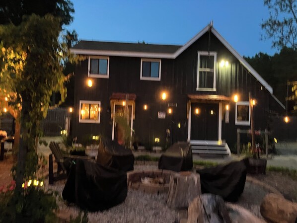 A two-story building with a porch, multiple windows, and outdoor seating.