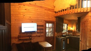 A wooden cabin interior with a television, a dining area, and a kitchen. - Cozy cabin in pleasant Little River perfect 4 a relaxing getaway.6 min 2beach.  (Little River)