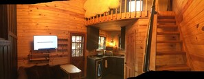 A wooden cabin interior with a television, a dining area, and a kitchen.