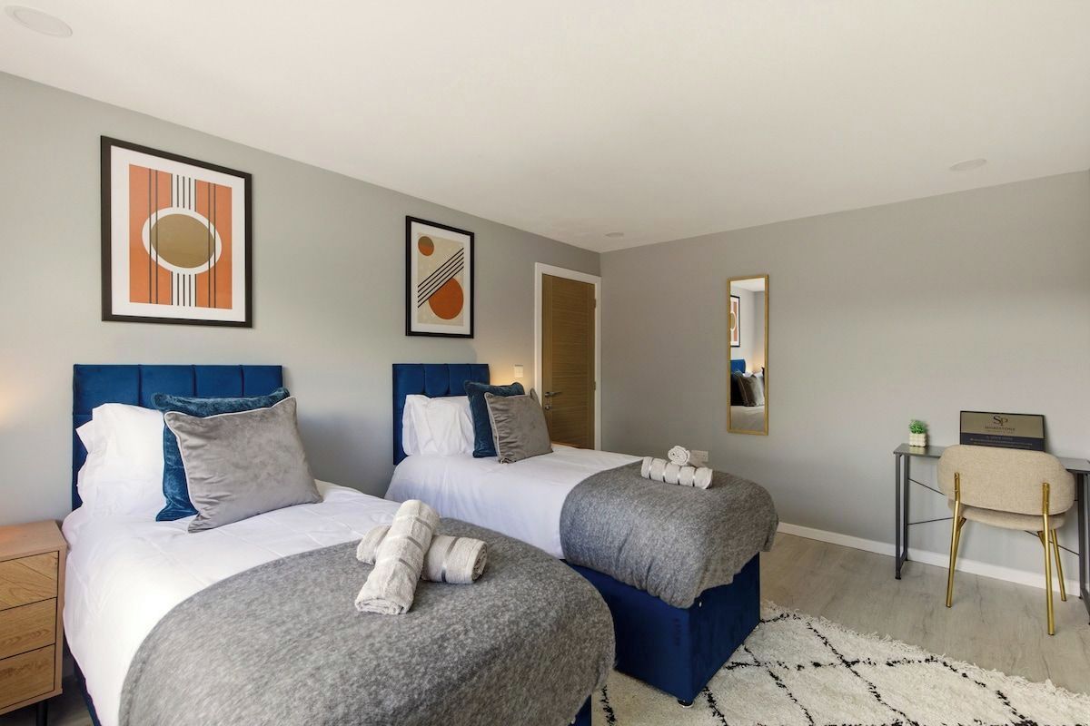 A hotel room with two beds, a desk, and a chair.