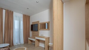 Una habitación moderna con un escritorio de madera, un televisor y una mesita.