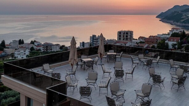 Terraza en la azotea con mobiliario exterior y vista al mar al atardecer.