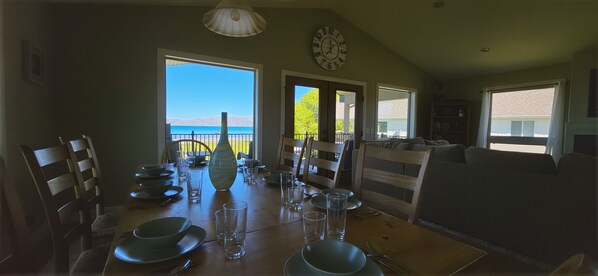 A dining area with a table set for a meal, chairs, a clock, and a view of the outdoors.