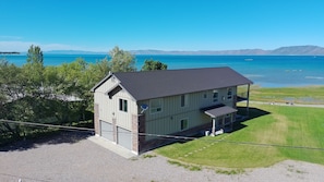 A two-story house with a covered porch, a garage, and a view of a lake and mountains.