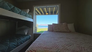 Una stanza con letti a castello, una finestra vista mare e un letto con copriletto a motivi floreali.