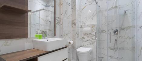 A modern bathroom with a glass shower enclosure, a white sink, and a wooden vanity.