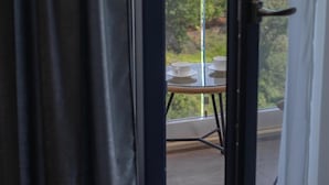 Blick durch eine Glastür auf einen Balkon mit Tisch und Stühlen.