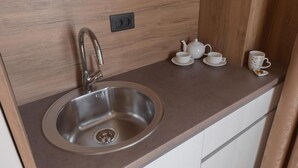 Una cocina con un lavamanos de acero inoxidable, encimera de madera y un juego de té.