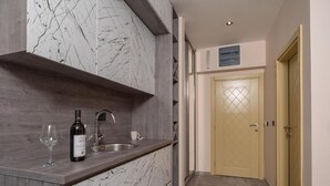 Una cocina con protector de salpicadero de mármol, encimera de madera, pileta de acero inoxidable y una botella de vino.