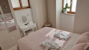 Ein Schlafzimmer mit einem Bett, einem Schminktisch mit Spiegel und einem kleinen Tisch.