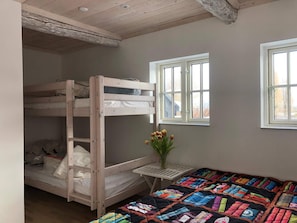 Ein Schlafraum mit Etagenbetten, einem Fenster und einem kleinen Tisch mit Blumen.