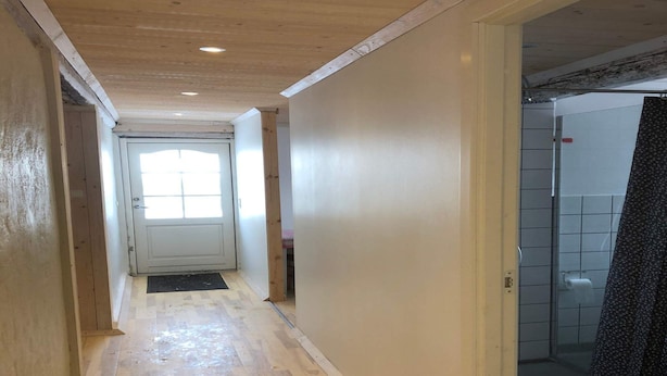 A hallway with wooden flooring, a white door at the end, and a tiled bathroom visible to the right. - 4 Star Holiday Home in Rudkobing (Rudkobing)