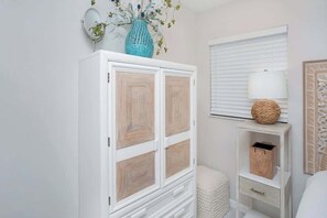 Ein weißer Kleiderschrank mit Spiegel und einer Blumenvase darauf.