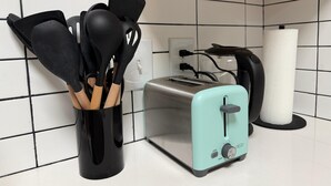 Una cocina con un tostador, un dispensador de toallas de papel y un recipiente para utensilios.