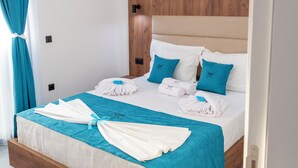 Una cama bien tendida con colcha azul y blanca, cabecera de madera y suelo de baldosas de mármol.