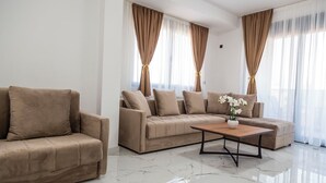 Una sala de estar moderna con un sofá color beige, una mesa de centro de madera y un jarrón con flores.