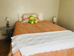 A neatly made bed with a plaid pillow, a green plush toy, and two bedside lamps.