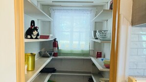 Une cuisine de taille réduite avec des meubles blancs, une statuette de chat noir et blanc, et un extincteur.