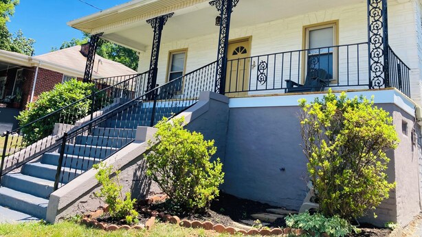 Une maison à deux étages avec un porche, un escalier et un petit jardin.