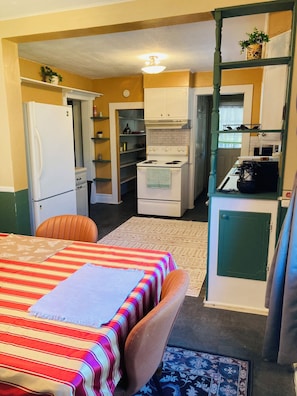 A compact kitchen with a refrigerator, stove, and sink. There is a dining area with a table and chairs.