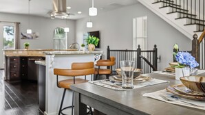 Une cuisine moderne dotée d’un îlot central, de tabourets de bar et d’une table à manger pour quatre personnes.