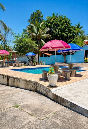 Un área de piscina con diversas opciones de asientos y sombrillas.