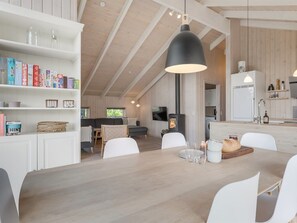 Ein modernes Interieur mit Essbereich, Bücherregalen, Kamin und Küche.