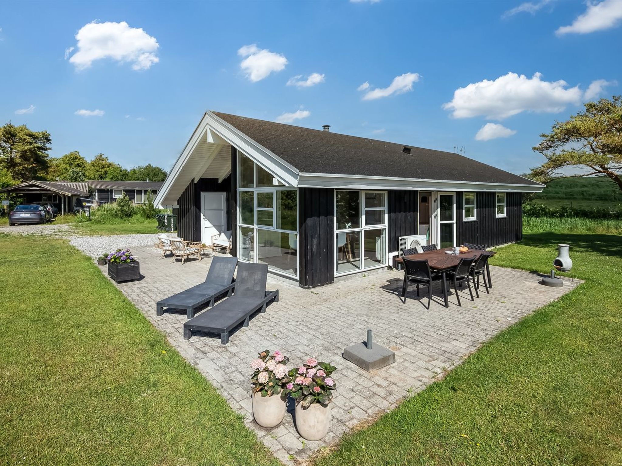 A modern house with a patio, outdoor seating, and a large glass door.