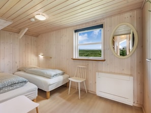 Ein Zimmer mit zwei Betten, einem Sessel, einem Fenster mit Blick und einer Heizung.