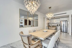 Eine moderne Küche mit Edelstahlgeräten, einem Holzespeiseesstisch und einer Kristallleuchter.