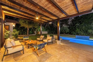 An outdoor patio with seating, a pool, and a covered area with a ceiling fan. - Casa Pochote | Private Saltwater Pool & Golf Retreat in Hacienda Pinilla (Tamarindo)
