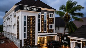 Un hôtel à la façade moderne, doté de nombreuses fenêtres, avec une voiture garée devant.