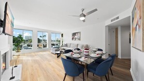 Un espace repas moderne avec une table en verre, des chaises bleues et un ventilateur de plafond.