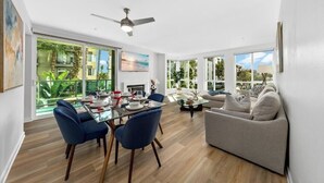 Un salon moderne avec un coin repas, de grandes fenêtres et un ventilateur de plafond.