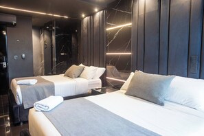A modern hotel room with two beds, a large mirror, and a marble wall. - Aman Luxury 23 Bedroom 3 Pool (Medellín)