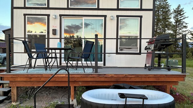 Et moderne hus med terrasse, udendørs møbler og et spabad.