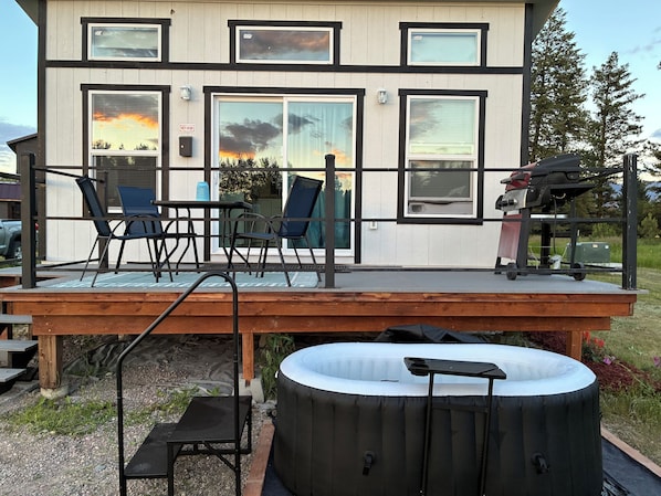 A modern house with a deck, outdoor seating, and a hot tub.