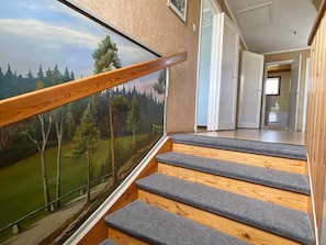 A staircase with wooden steps and a view of a forest through a glass panel.