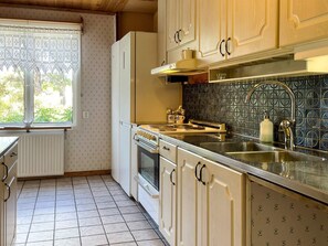 Eine Küche mit Fenster, Kühlschrank, Herd und Spüle.