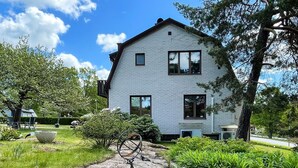 Ett tvåvåningshus med en fasad av tegel, en veranda och en uppfart som leder fram till entrén.