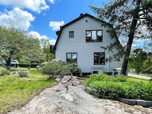 A two-story house with a brick exterior, a front porch, and a driveway leading to the entrance.