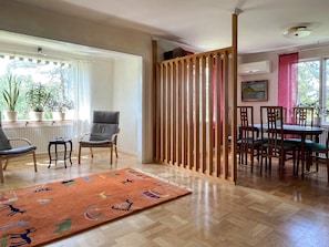 A room with a wooden partition, a dining area with chairs and a table, and a window with plants. - 5 Person Holiday Home in Gunnebo (Gunnebo)